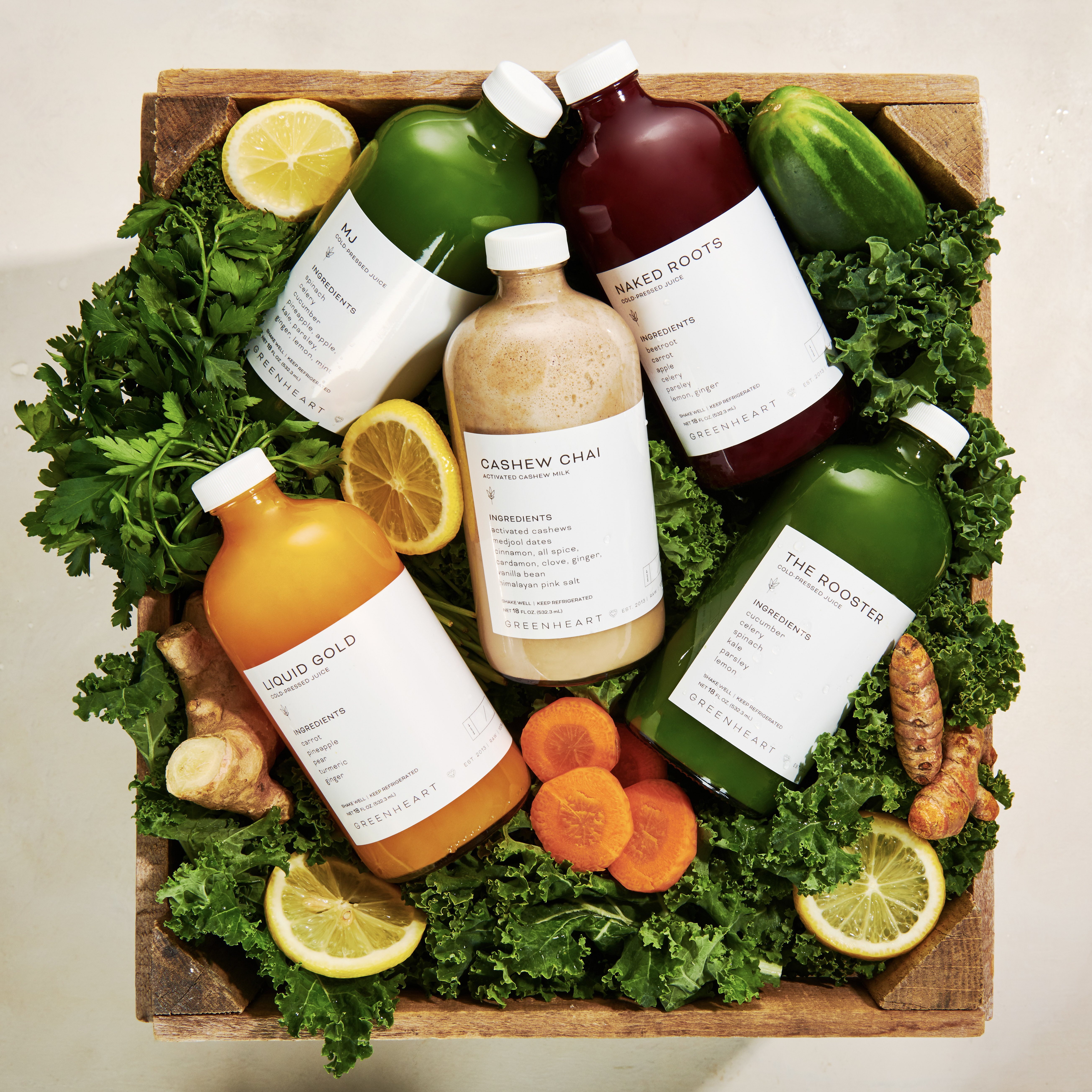 Photo of Greenheart juices laid over a bed of fruits and veggies.